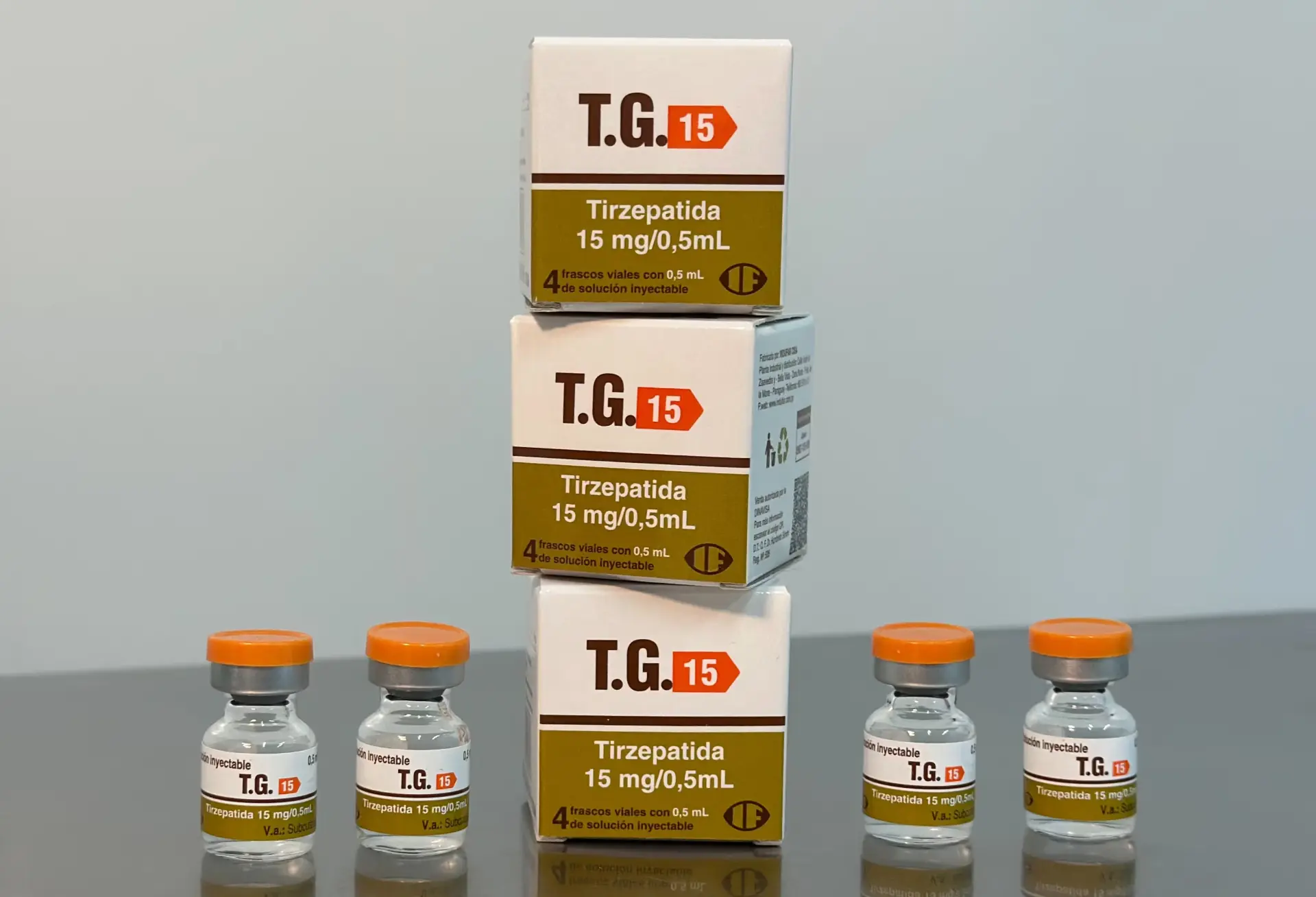 Três caixas de T.G. 15 Tirzepatida 15 mg/0,5 mL empilhadas ao lado de quatro frascos com tampa laranja